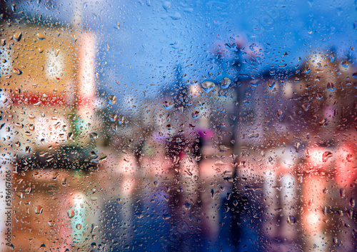 City view through a window on a rainy night,Rain drops on window with road light bokeh, City life in night in rainy season abstract background. Focus on drops on glass 