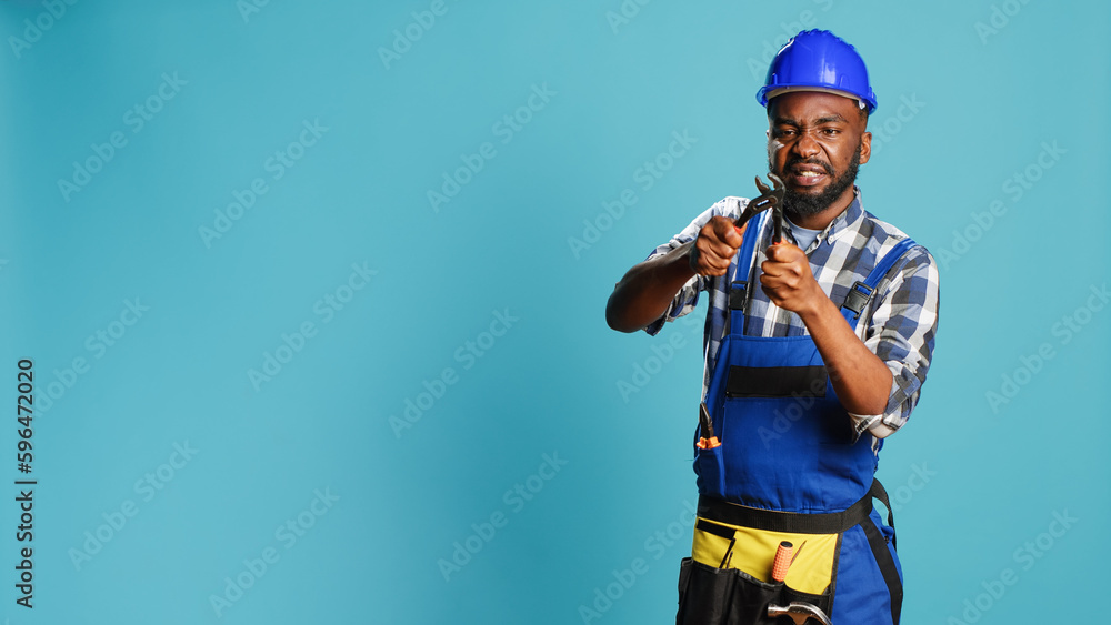 Professional contractor tightening with wrench, using spanner tool to fix and clamp on camera. Young builder with overalls doing carpentry work in studio, steel instrument key. Professional contractor tightening with wrench, using spanner tool to fix and clamp on camera. Young builder with overalls doing carpentry work in studio, steel instrument key.