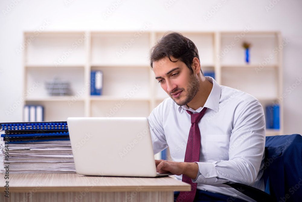 Young male employee and too much work in the office Young male employee and too much work in the office