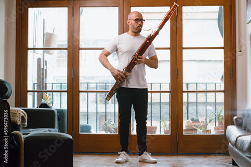 Obraz na plátně young latin man venezuelan musician in his living room standing playing the bass