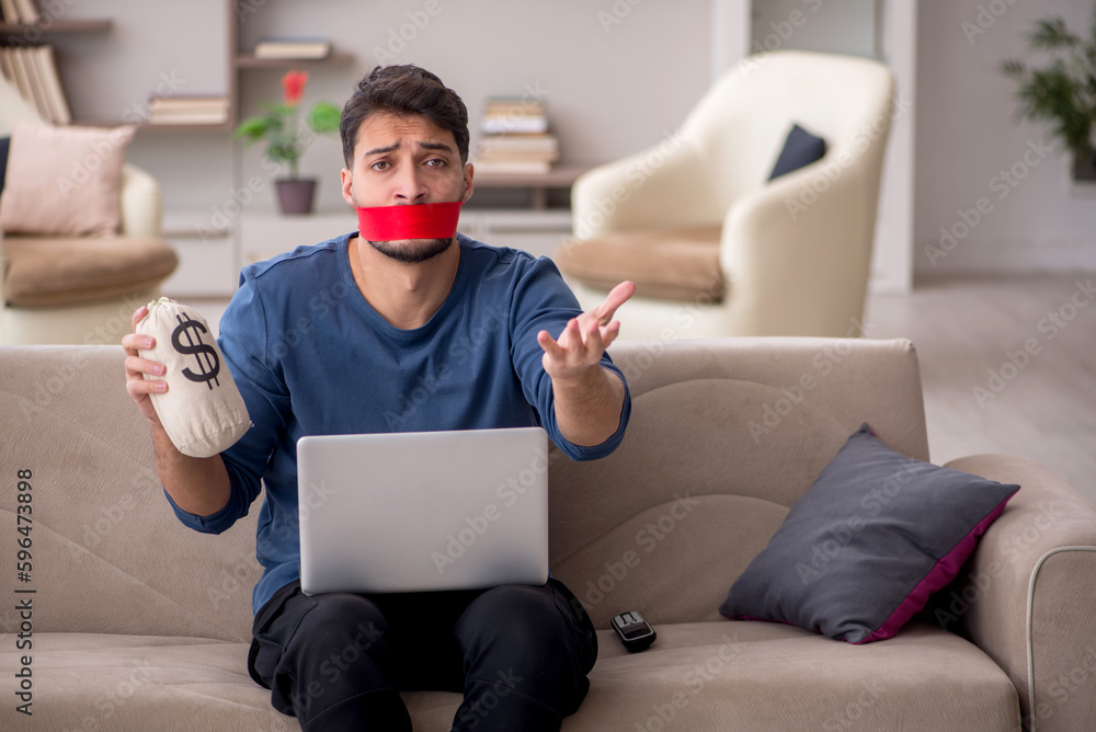 Mouth closed young man holding moneybag at home Mouth closed young man holding moneybag at home