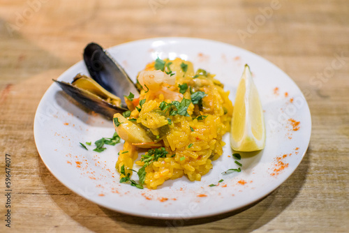 Restaurant dish served on the table. Rice with saffron and seafood. accompanied by a mussel and a lemon
