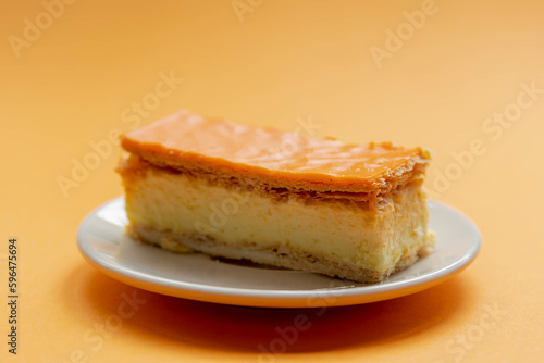 Celebration of the National holiday King’s Day (Koningsdag in Dutch) Selective focus of orange Tompouce in white plate on orange background, A tompoes is a pastry in the Netherlands. photo