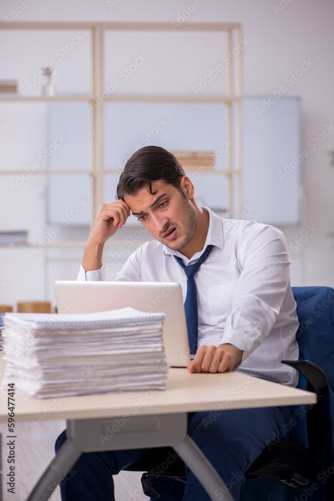 Young male employee and too much work in the office Young male employee and too much work in the office