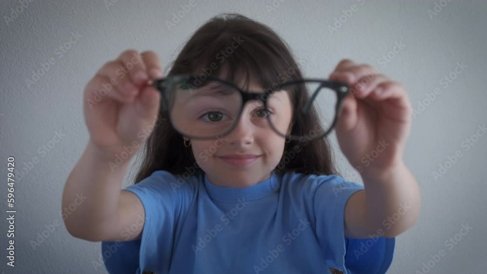 Child look through the lenses of glasses. A pretty little girl look through glasses lens for vision in the room. Child look through the lenses of glasses. A pretty little girl look through glasses lens for vision in the room.