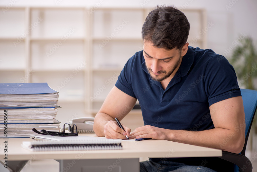 Young male employee sitting at workplace Young male employee sitting at workplace