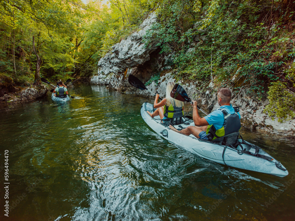 A group of friends enjoying having fun and kayaking while exploring the calm river, surrounding forest and large natural river canyons A group of friends enjoying having fun and kayaking while exploring the calm river, surrounding forest and large natural river canyons