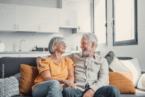 Happy laughing older married couple talking, laughing, standing in home interior together, hugging with love, enjoying close relationships, trust, support, care, feeling joy, tenderness.