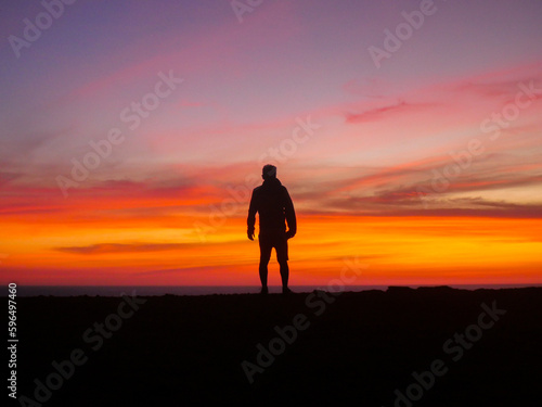 Contemplative View with Middle-Aged Man Silhouette on Cliff Edge and Sunset Sky