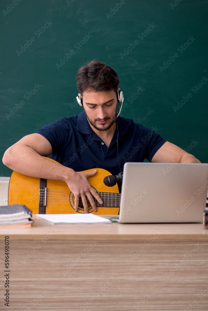 Young male music teacher sitting in the classroom Young male music teacher sitting in the classroom