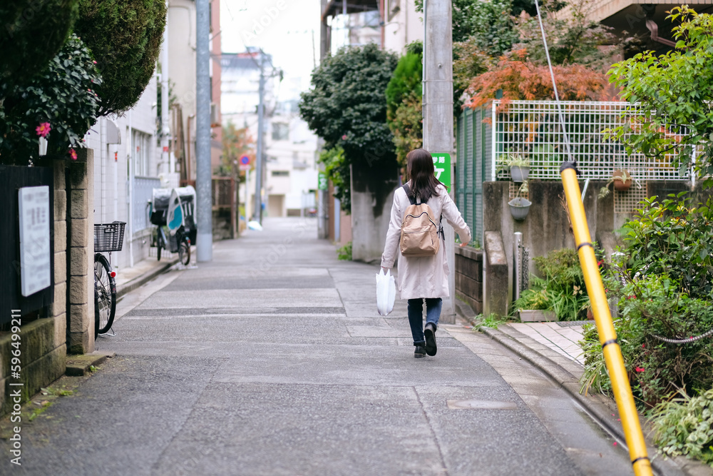 買い物袋を持って街を歩く女性の後ろ姿