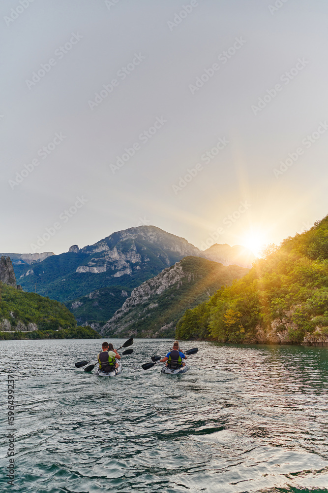 A group of friends enjoying fun and kayaking exploring the calm river, surrounding forest and large natural river canyons during an idyllic sunset.