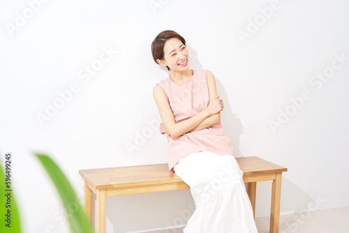 ベンチに座るミドルエイジ女性のポートレート コピースペース 白背景