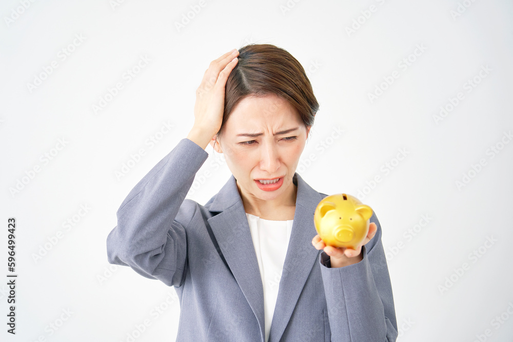 貯金箱を持って頭を抱えるビジネスウーマン　白背景