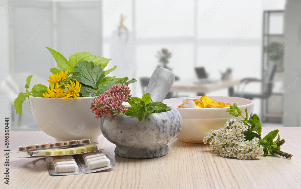 Mortar with fresh herbs and pills on wooden table in medical office - obrazy, fototapety, plakaty 