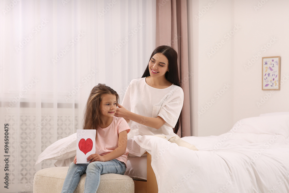 Happy woman and her daughter spending time together on bed at home, space for text. Mother's day celebration