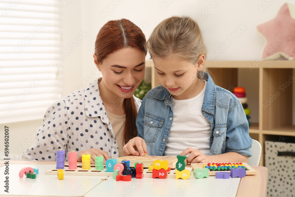 Happy mother and daughter playing with different math game kits at desk in room. Study mathematics with pleasure Happy mother and daughter playing with different math game kits at desk in room. Study mathematics with pleasure