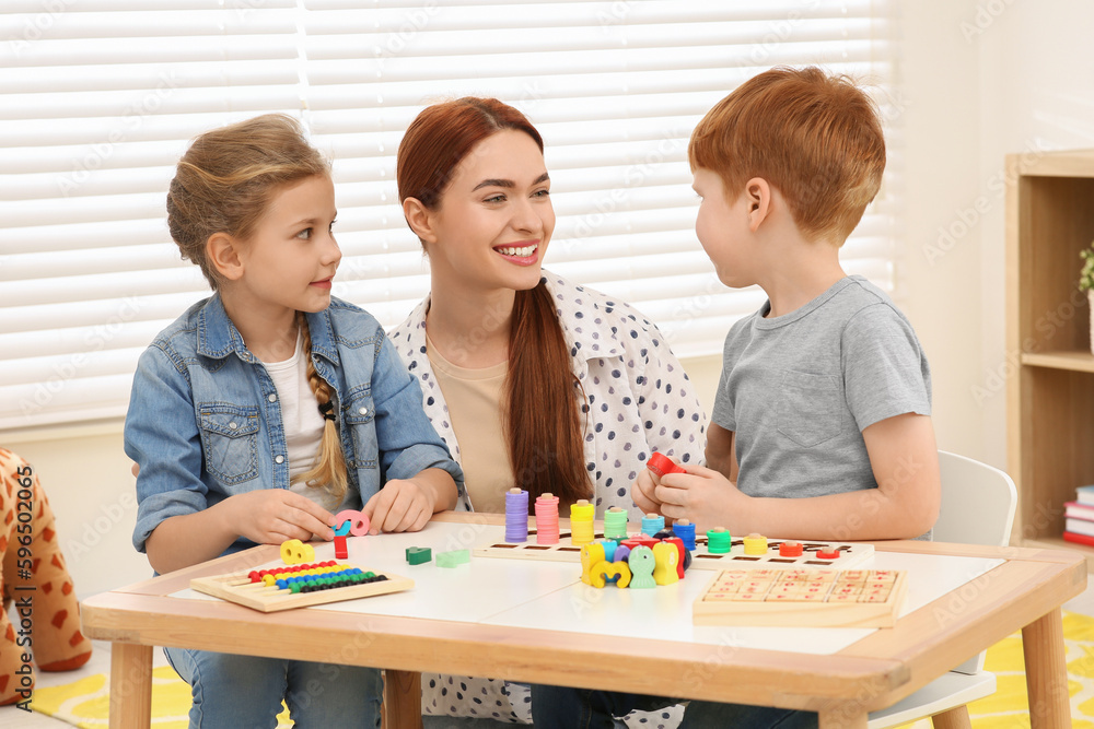 Fototapeta premium Happy mother and children playing with different math game kits at desk in room. Study mathematics with pleasure