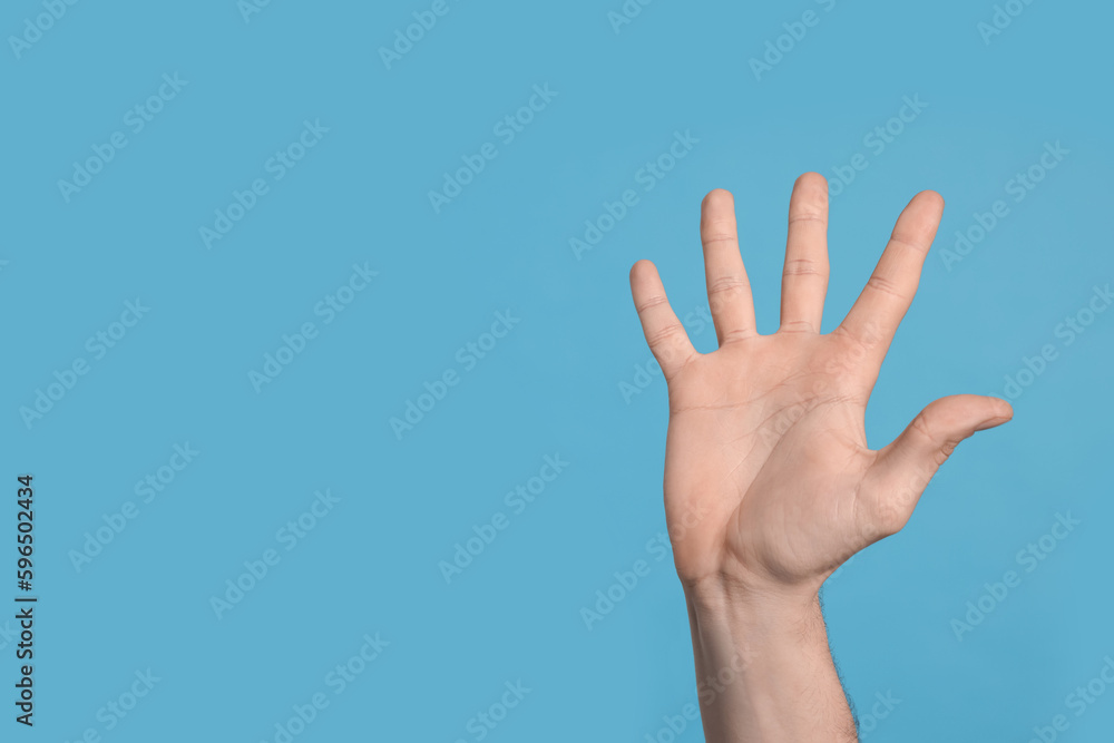Man giving high five on light blue background, closeup of hand. Space for text Man giving high five on light blue background, closeup of hand. Space for text