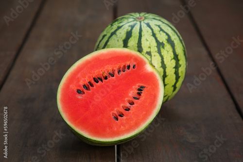 Delicious cut and whole ripe watermelons on wooden table
