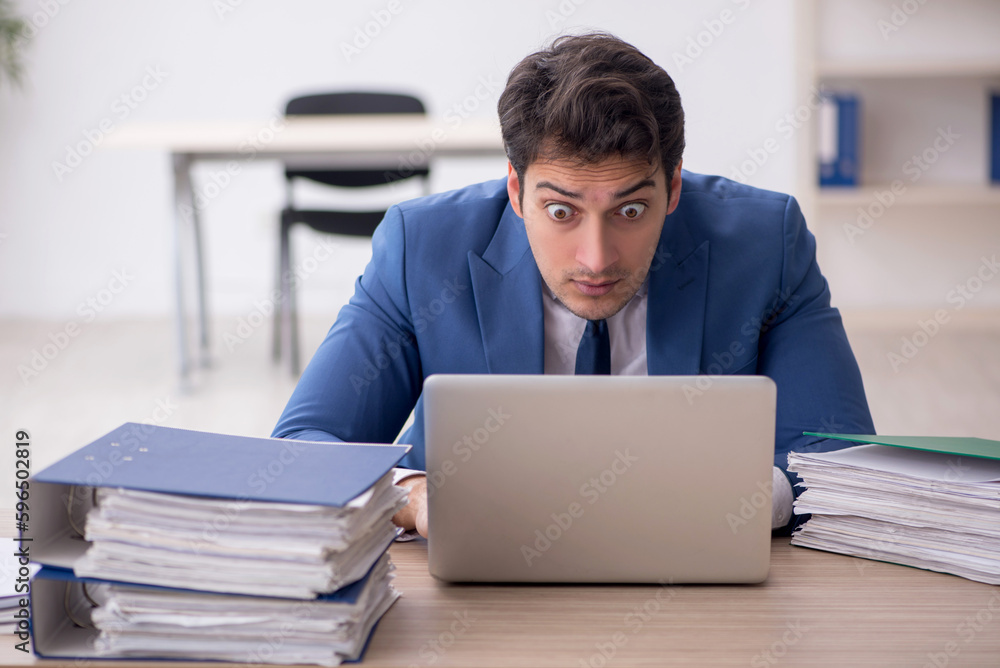 Young male employee and too much work in the office Young male employee and too much work in the office