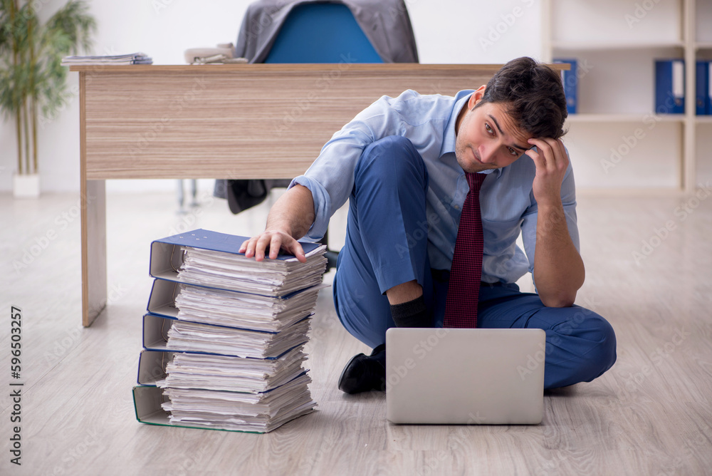 Obraz premium Young male employee unhappy with excessive work in the office