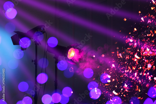Bright spotlights, beams of light and falling shiny confetti in night club, bokeh effect