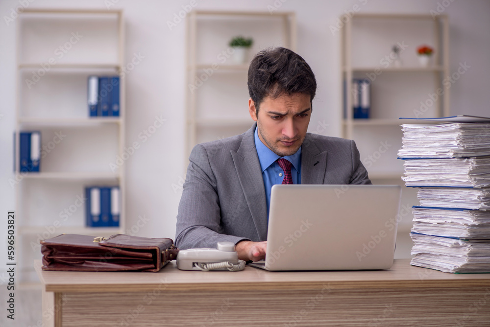 Young male employee and too much work in the office Young male employee and too much work in the office