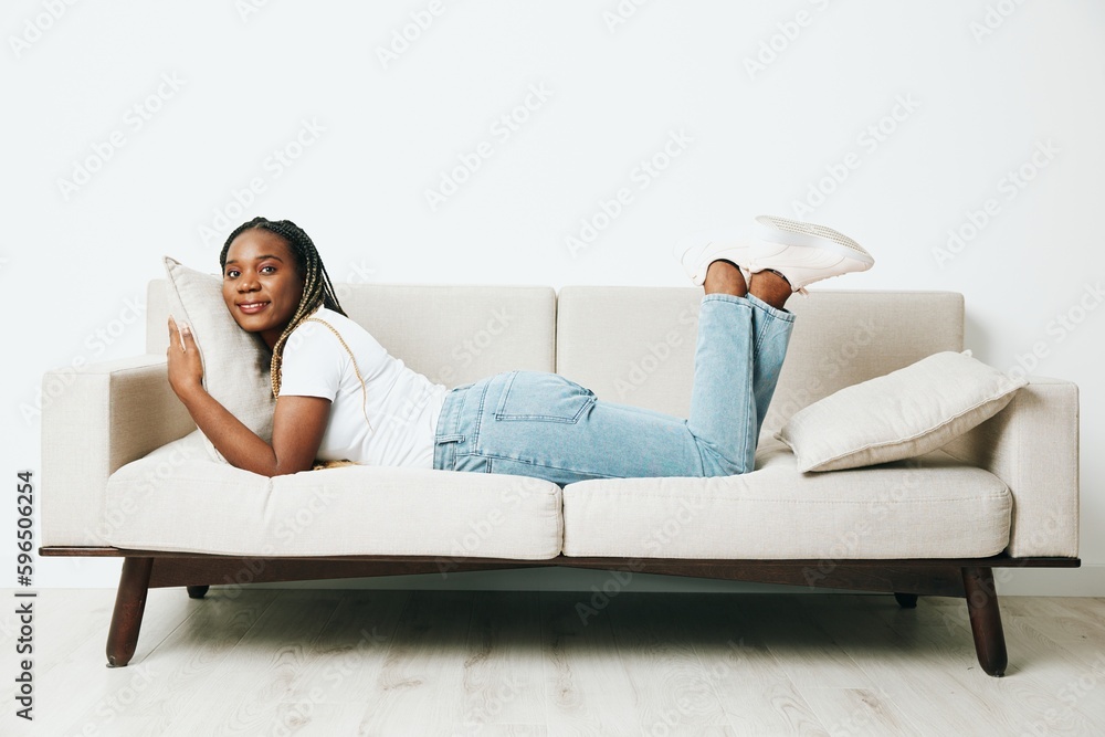 Happy african american woman sleeping at home on the sofa, rest and vacation smile, light background, daytime sleep, fatigue depression. Relaxed home lifestyle, day off.
