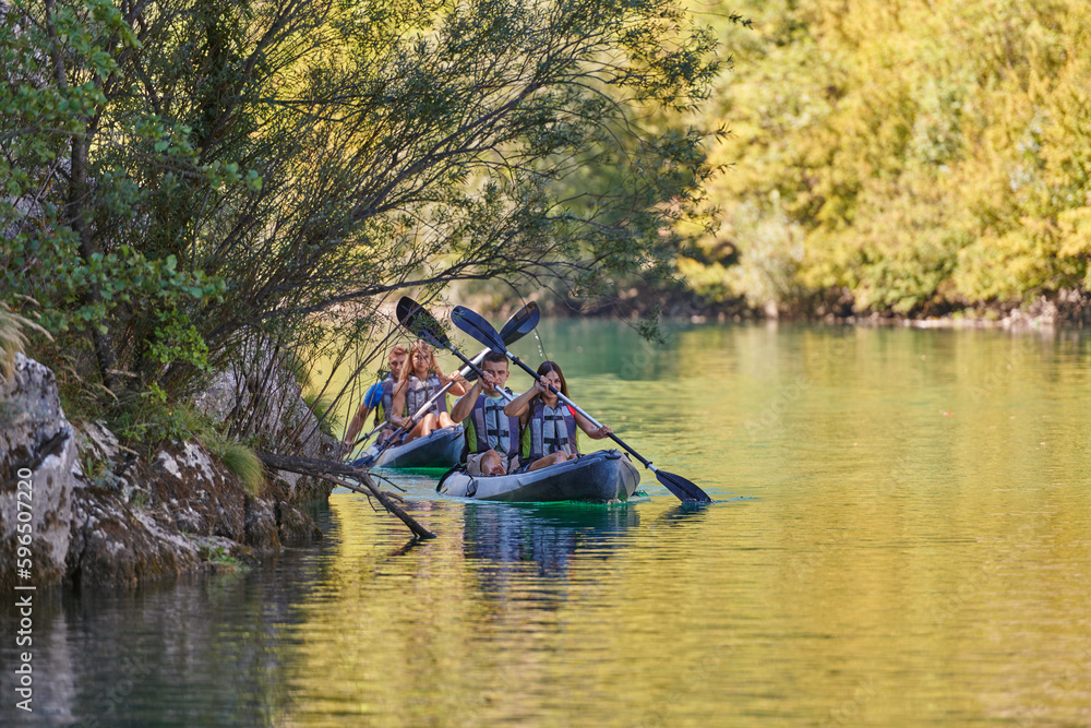 Fototapeta premium A group of friends enjoying having fun and kayaking while exploring the calm river, surrounding forest and large natural river canyons