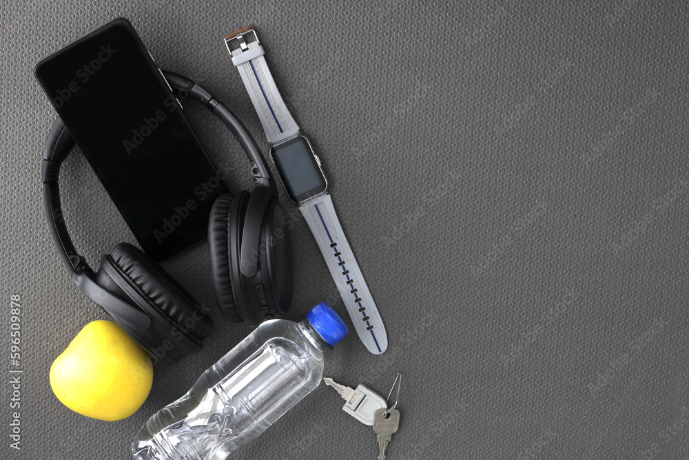 Items for exercising on a yoga mat such as headphones, cell phone, water, towel and apple for a healthy life and well-being Items for exercising on a yoga mat such as headphones, cell phone, water, towel and apple for a healthy life and well-being