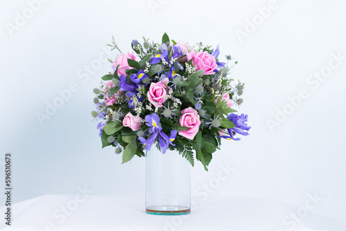 Many kinds of flowers placed in a brightly colored vase in a white setting