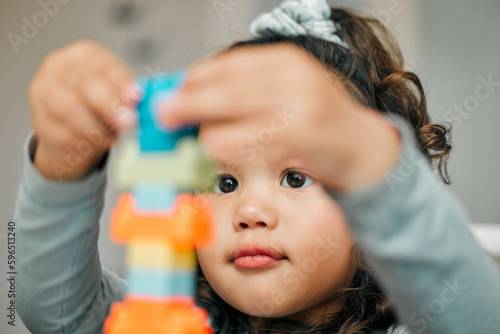Focused and determined. Shot of a cute little girl playing with building blocks at the kitchen table.