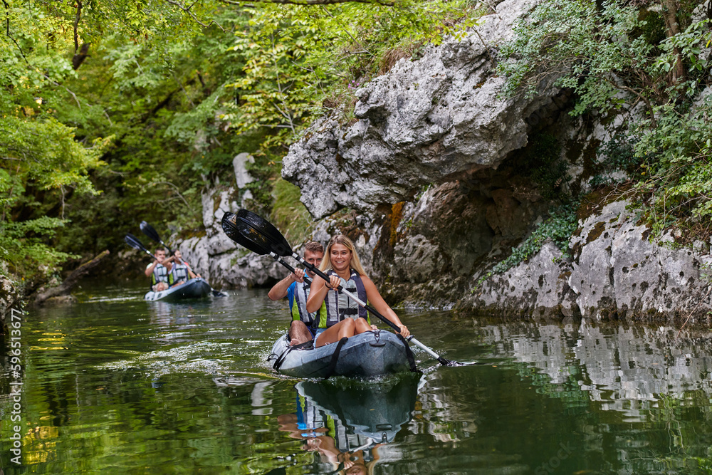 A group of friends enjoying having fun and kayaking while exploring the calm river, surrounding forest and large natural river canyons A group of friends enjoying having fun and kayaking while exploring the calm river, surrounding forest and large natural river canyons