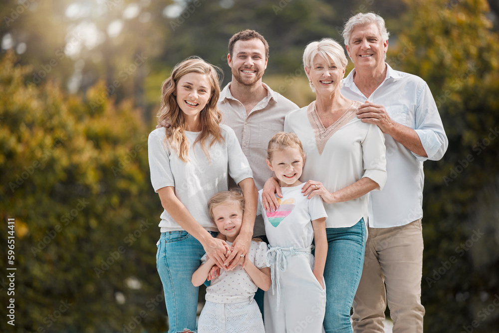 Portrait of a smiling multi generation caucasian family standing close together in the garden at home. Happy adorable girls bonding with their mother, father, grandfather and grandmother in a backyard