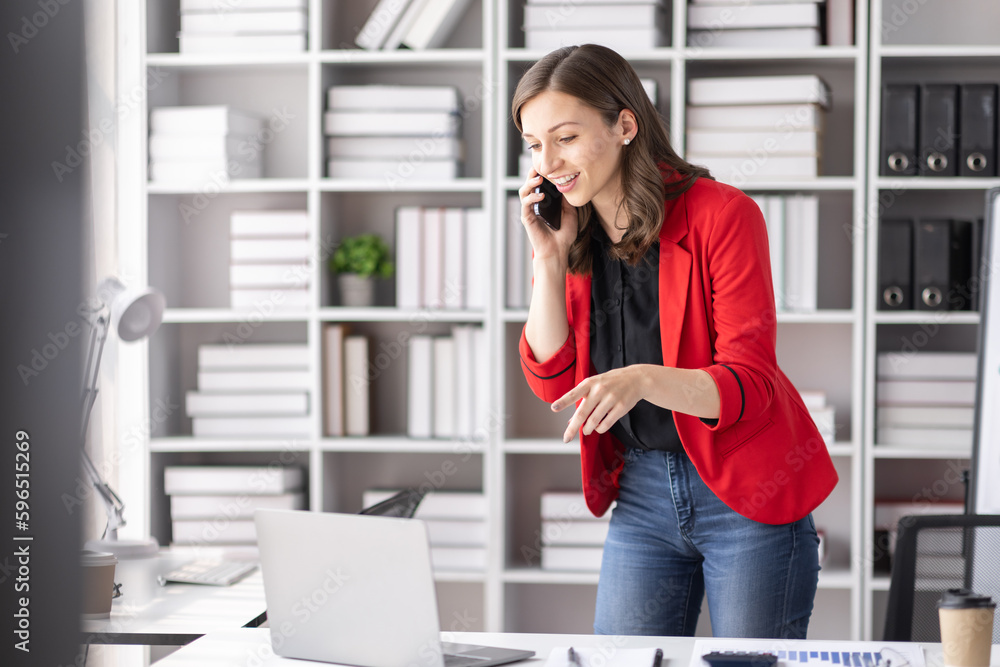 Cheerful business Asian Canadian woman freelancer making telephone call share good news about project working in office workplace, business finance concept. Cheerful business Asian Canadian woman freelancer making telephone call share good news about project working in office workplace, business finance concept.