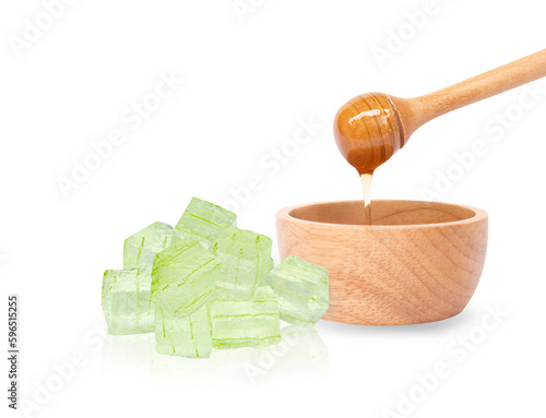Closeup honey dripping into wooden bowl with alovera cube gel isolated on white background, Skin care and spa beauty concept