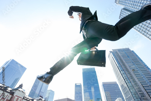 空をローアングルでジャンプするスーツの1人のビジネスマン