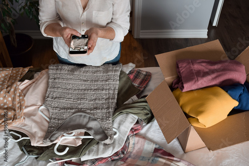 Woman is taking a picture of her unwanted clothing items to resale online photo