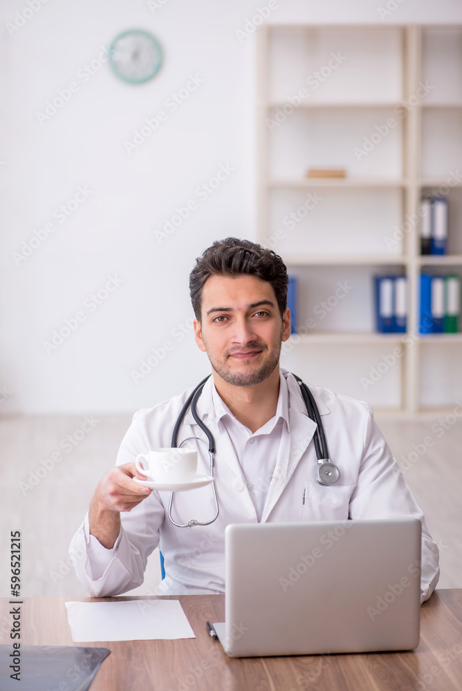 Young male doctor drinking coffee during break Young male doctor drinking coffee during break