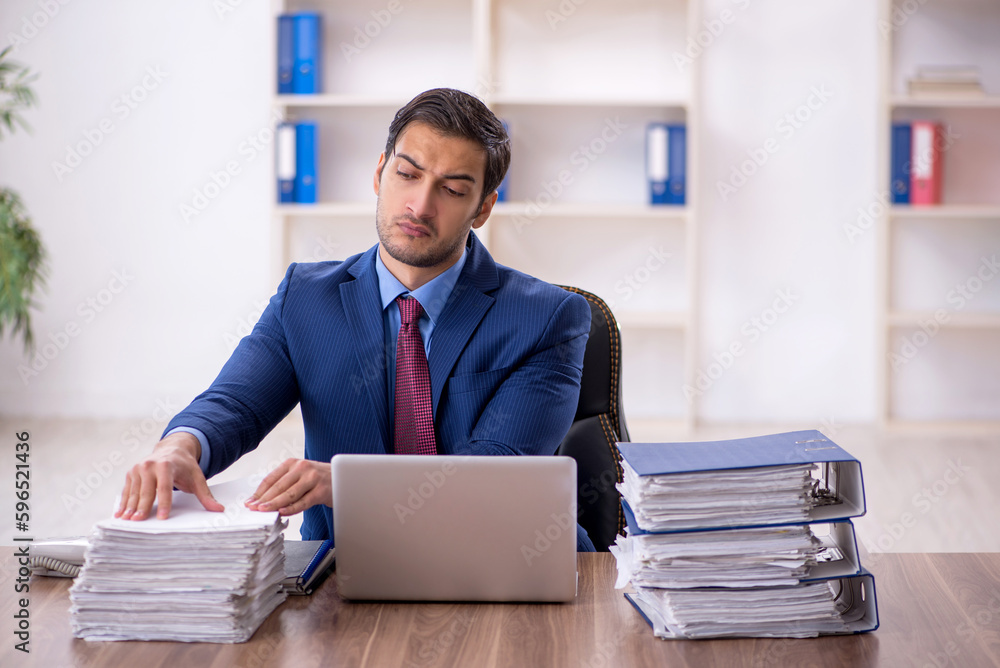 Young male employee and too much work in the office Young male employee and too much work in the office