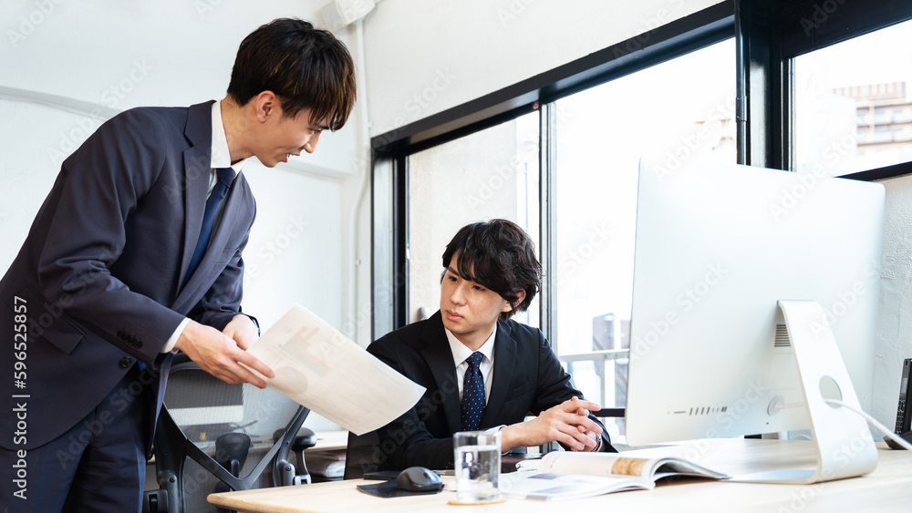 真剣な表情で部下の報告と相談を受ける30代の管理職の男性 真剣な表情で部下の報告と相談を受ける30代の管理職の男性