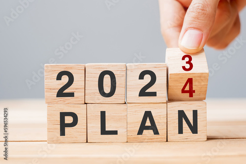hand flipping block 2023 to 2024 PLAN text on table. Resolution, strategy, goal, motivation, reboot, business and New Year holiday concepts photo