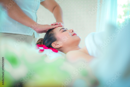 Side view of the professional masseuse is skillfully giving an herbal massage on a comfortable bed sprinkled with rose petals.