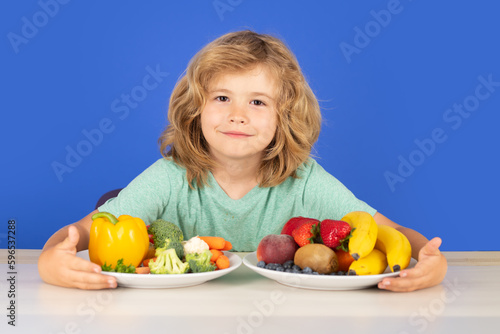 Fruits and vegetables for children. Healthy kids food. Closeup face of kid eating organic food, yogurt, milk. Child healthy eat. Smiling little boy eating food on kitchen.