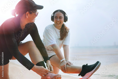 two asian woman stretching muscle and preparing to exercise on sea beach with happiness photo