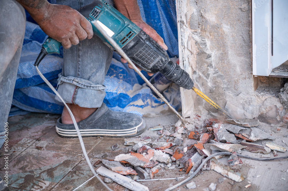 Obraz premium Close-up hands of worker drilling and remove a tile on the wall with breaker machine