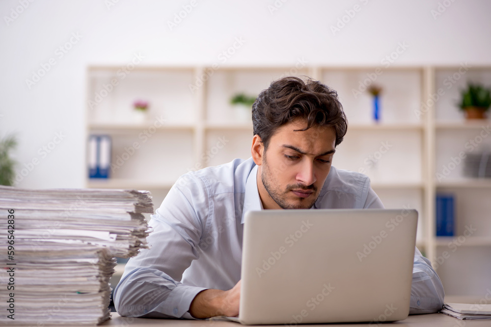 Young male employee and too much work in the office Young male employee and too much work in the office