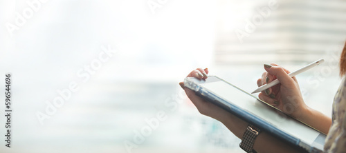 Digital signature, electronic note taking. Close up view of woman holding stylus pen signing electronic documents via digital application in tablet photo