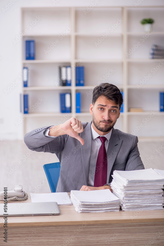 Young male employee and too much work in the office Young male employee and too much work in the office
